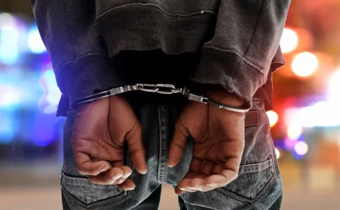 Person in handcuffs with blurred lights in background.