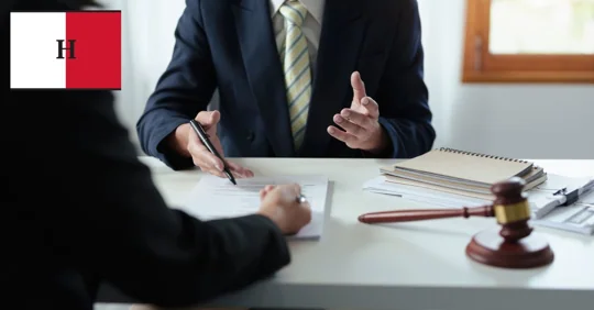 Two people discussing legal documents at a desk with a gavel.